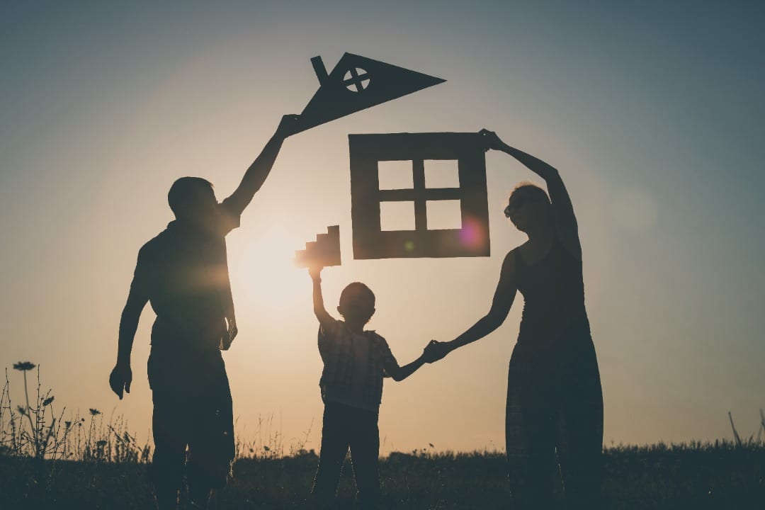 Silhouette of a family holding various parts of a cut out of a house.