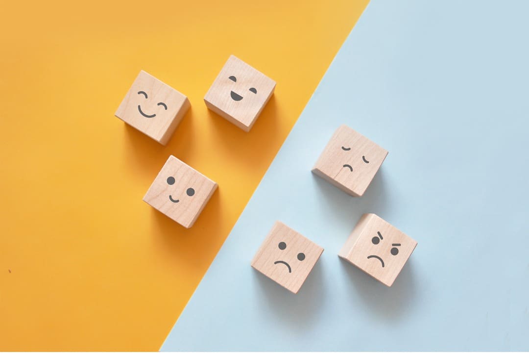 Six different faces depicting different emotions on wooden cubes.