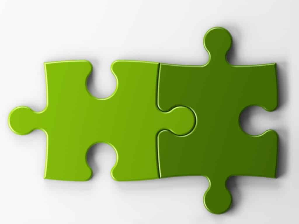 Two green puzzle pieces fitted together. One is dark green, the other light green.
